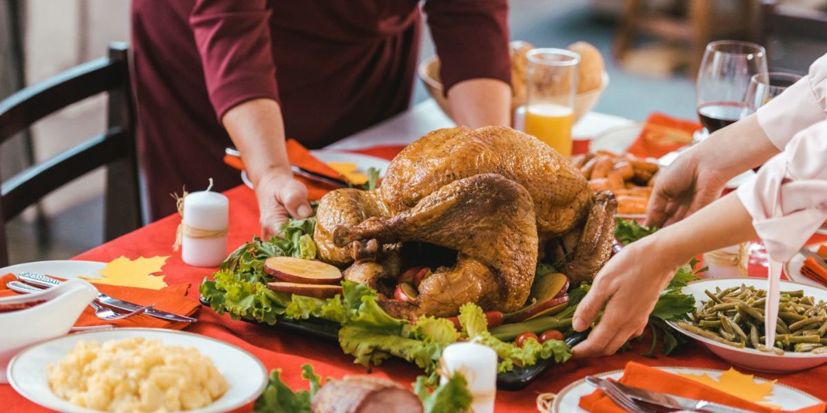 person placing a turkey on a thanksgiving table