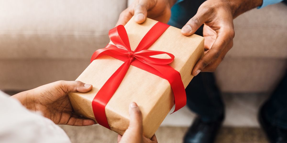 person handing gift with bow to another person